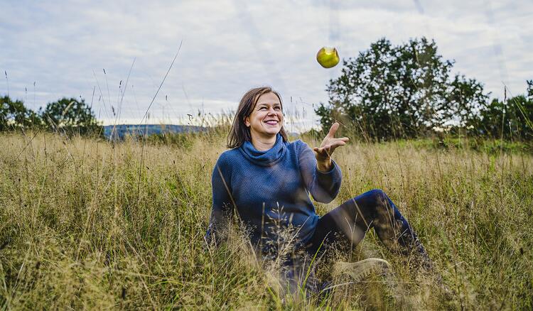 Tanja Busse mit einem Apfel auf einer Wiese